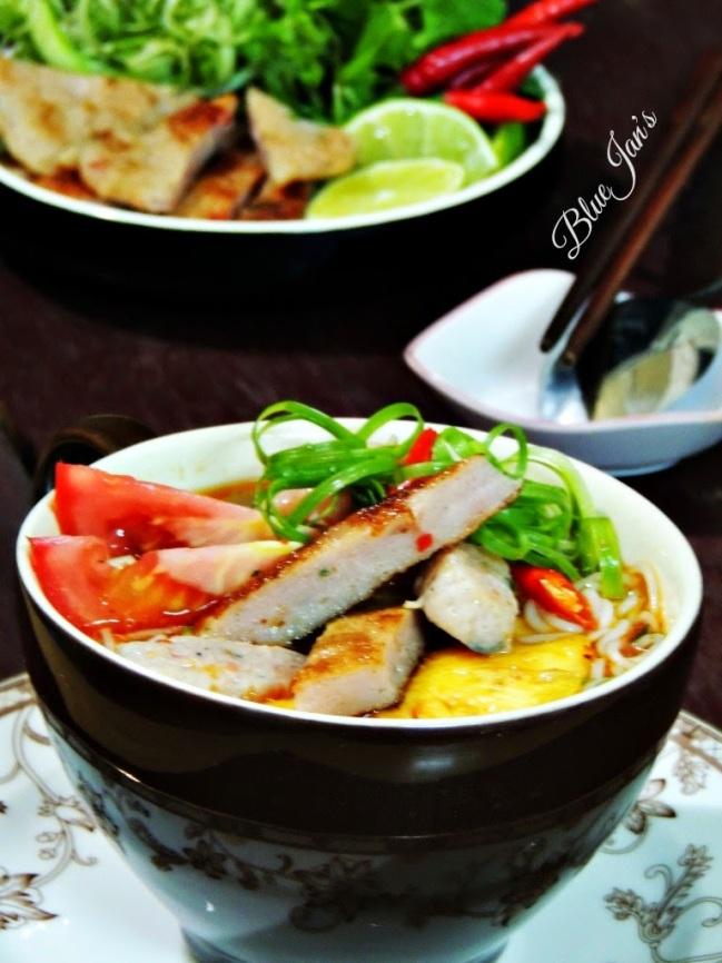 Nồi nước dùng bún chả cá đang sôi liu riu với xương cá, thơm, cà chua và rau củ, nước trong veo