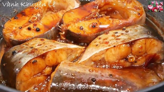 Hành tỏi đang được phi thơm vàng trong nồi đất cùng nước màu, chuẩn bị cho bước kho chả cá theo cách nấu cách kho chả cá